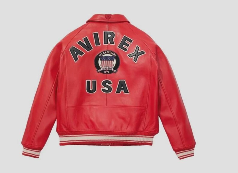 May include: A red leather jacket with the word "AVIREX" arched across the shoulders in black letters. Below the word "AVIREX" is a patch with the words "ALL AMERICANS" and "USA" in black letters. The jacket has white and red striped cuffs.