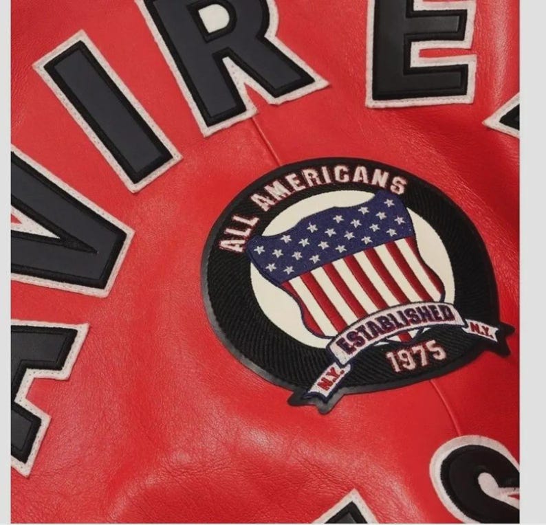 May include: Close-up of a red leather jacket with black and white lettering. A circular patch features the American flag and the words "ALL AMERICANS ESTABLISHED 1975 N.Y."