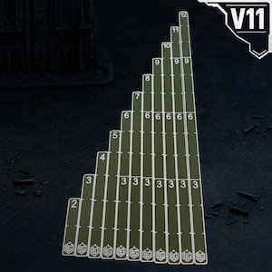 May include: An olive green measurement tool featuring eleven vertical strips of varying heights, each marked with white numbers ranging from two to twelve and a small logo at the base. The top right corner displays the white text V11.