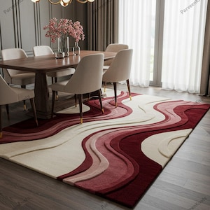 Può includere: Un tappeto rettangolare con un design ondulato nei toni del rosso, crema e rosa. Il tappeto è posto sotto un tavolo da pranzo e sedie, aggiungendo un elemento decorativo alla stanza. Il design del tappeto crea un senso di movimento e interesse visivo.