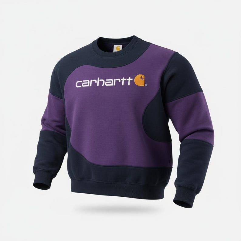 Puede incluir: Una sudadera Carhartt en azul marino y morado. La sudadera presenta el nombre de la marca en blanco en el pecho, con un logotipo naranja. Las mangas y la parte superior son azul marino, mientras que el centro es morado.