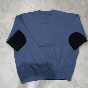May include: A blue sweatshirt with black elbow patches. The long-sleeved top is a solid blue color with a crew neck and black patches on the elbows. The garment is made of a soft material.