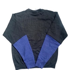 Op de afbeelding: Een donkergrijs sweatshirt met blauwe mouwen. De mouwen zijn effen blauw, terwijl de body van het sweatshirt donkerder grijs is. Het sweatshirt is gemaakt van een zacht materiaal.
