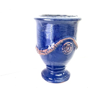 Peut inclure: Un vase en céramique bleu cobalt avec une base en piédestal et un large bord. Une spirale décorative texturée, marron, entoure le vase. Le vase mesure environ 20 cm de haut.