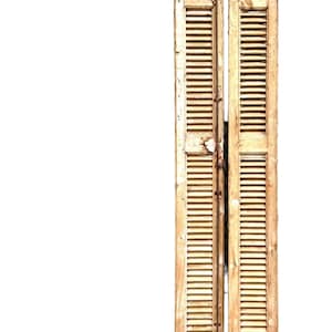 May include: Two vintage wooden shutters with horizontal slats, painted in a distressed, off-white color. The shutters are hinged together and show signs of wear, with peeling paint and a rustic aesthetic. Ideal for home decor.