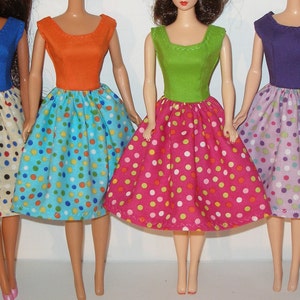 May include: Six dolls wearing different colored dresses with white polka dots. The dresses are all the same style, with a fitted bodice and a full skirt.