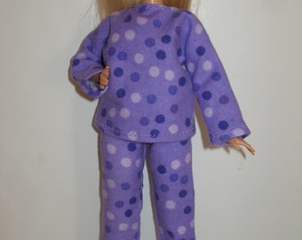 May include: Purple and white polka dot pajamas for a doll. The pajamas have long sleeves and long pants.