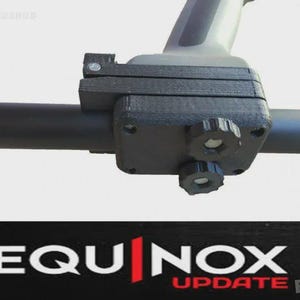 May include: A black metal detector component with the text "EQUINOX UPDATE" in white and red. The component has a handle and adjustable knobs. The image is a close-up shot.