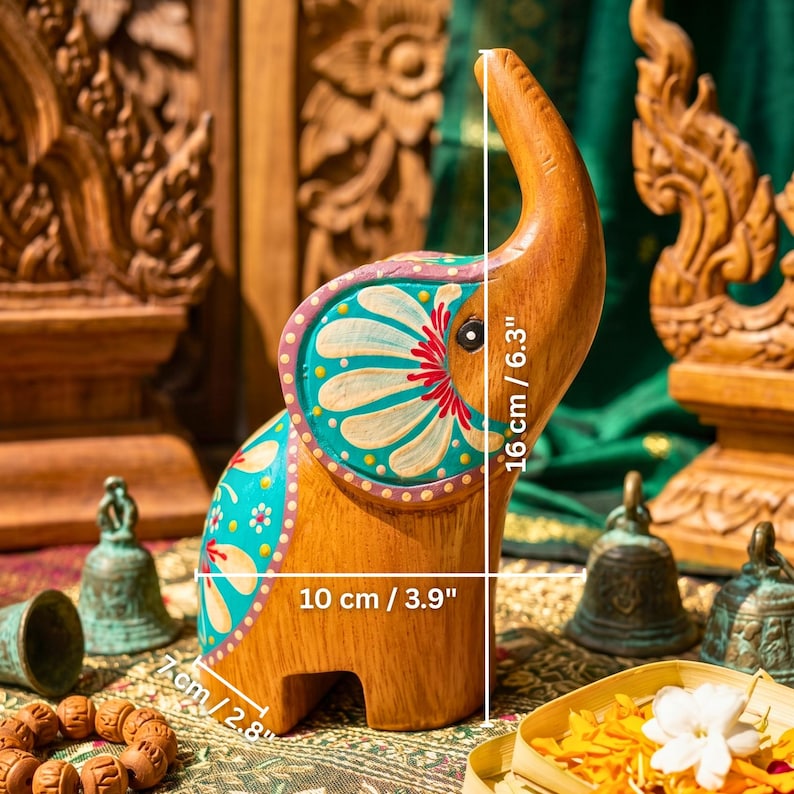 May include: Wooden elephant figurine, 6.3 inches tall, with hand-painted turquoise, pink, and white floral designs. The elephant is 3.9 inches long and 2.8 inches wide, showcasing intricate details and craftsmanship. A decorative item.