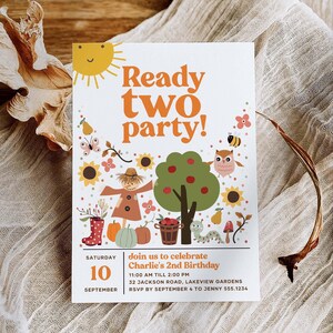 May include: A colorful invitation for a child's second birthday party. The invitation features a cartoon sun, a scarecrow, a tree with apples, and a caterpillar. The text on the invitation reads "Ready two party!" and includes the date, time, and location of the party.