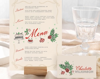 May include: A festive menu card and place card with a Christmas theme. The menu features a cream background with red and green illustrations and text. The place card has the name "Charlotte Wilkinson". Two clear glasses are on either side.