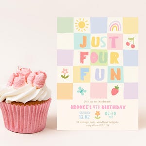May include: A cupcake with pink frosting in a pink wrapper next to a rectangular birthday invitation card. The card features a pastel checkered pattern with icons of a sun, rainbow, cherries, flower, butterfly, and strawberry, and the text JUST FOUR FUN.