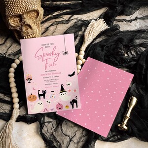 Puede incluir: Invitaciones rosas para una fiesta de Halloween con el texto "Spooky Fun" e ilustraciones tem&aacute;ticas de Halloween. La invitaci&oacute;n incluye detalles para una celebraci&oacute;n de cumplea&ntilde;os. Una calavera dorada y cuentas decorativas en el fondo.