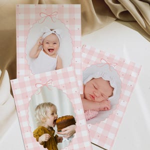 May include: Three pink and white gingham baby photo cards with oval frames and bow accents. Each card features a different baby photo. One card has the text "twelve months".