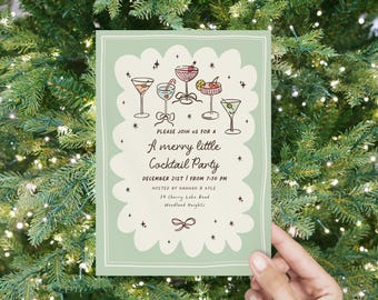 May include: A light green invitation with a scalloped border, featuring illustrations of cocktails. The text reads "A merry little Cocktail Party" with the date and time. The invitation is held in front of a Christmas tree.