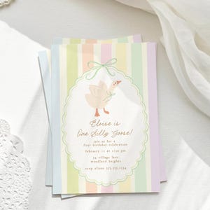 May include: A pastel-colored invitation card with a striped background. The card features a cartoon illustration of a white goose with a pink bow. The text on the card reads "Eloise is One Silly Goose!" and includes details for a first birthday celebration.