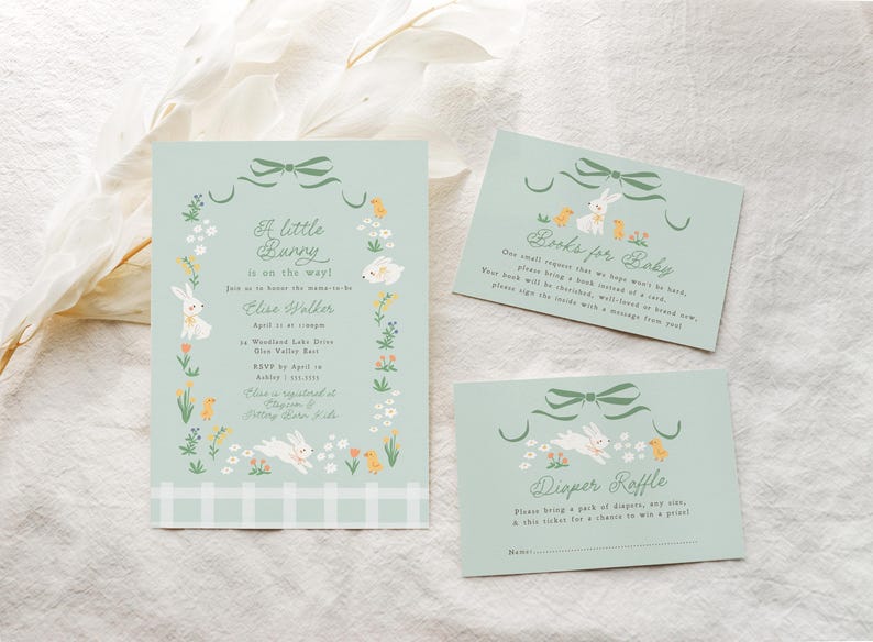 Pu&ograve; includere: Un invito a una festa di nascita di colore azzurro chiaro con un design di coniglietto e il testo "A little bunny is on the way!" L'invito include il nome "Elise Walker" e i dettagli della festa. Ci sono anche due biglietti per un libro e una lotteria di pannolini.