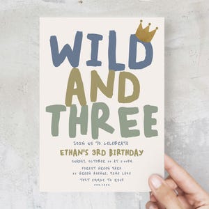 May include: A birthday invitation featuring the text "WILD AND THREE" in green, blue, and gold lettering. The invitation is for Ethan's 3rd birthday party, taking place on Sunday, 20th October at 2:00 PM at Forest Green Park. The address is 22 Green Avenue, Pine Lake. The text "TEXT EMHIE TO RSVP" is also included, along with the phone number 222.1234.