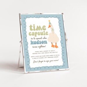 May include: A blue and white sign with a goose wearing a party hat. The sign says "time capsule to be opened when hudson turns eighteen!" Please take a moment to leave a message for a very special one year old! Write a note and share some words of advice, a piece of wisdom, or a treasured memory. Don't forget to sign your name!"