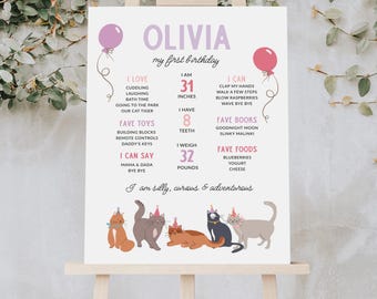 Könnte beinhalten: Personalisiertes Geburtstags-Schild auf einer Staffelei, mit dem Namen "Olivia" und Details über ihr erstes Jahr. Das Schild enthält eine Liste der Favoriten, Maße und eine Katzenillustration. Das Schild ist 78.7 cm hoch und wiegt 14.5 kg.