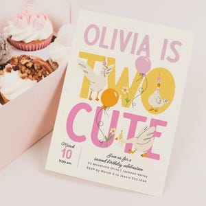May include: A birthday invitation with the text "OLIVIA IS TWO CUTE" featuring illustrations of geese and balloons. The invitation is cream-colored with pink and yellow accents. Cupcakes in a pink box are in the background.