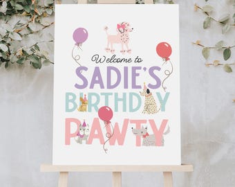 May include: A white sign on an easel with the text "Welcome to Sadie's Birthday Pawty." The sign features illustrations of dogs, balloons, and the text in purple, teal, and pink.