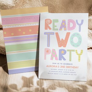 Pu&ograve; includere: Un invito di compleanno dai colori pastello con la scritta "READY TWO PARTY" in lettere colorate e giocose. L'invito &egrave; per il 2&deg; compleanno di Aurora e include i dettagli dell'evento. Un blocco note abbinato con strisce e pois pastello &egrave; accanto all'invito.