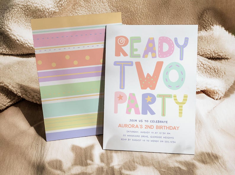 Pu&ograve; includere: Un invito di compleanno dai colori pastello con la scritta "READY TWO PARTY" in lettere colorate e giocose. L'invito &egrave; per il 2&deg; compleanno di Aurora e include i dettagli dell'evento. Un blocco note abbinato con strisce e pois pastello &egrave; accanto all'invito.
