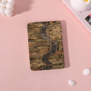 May include: A rectangular case with a vintage map design featuring a river winding through a landscape with buildings and trees. The case has a brown, green, and beige color scheme. The case is on a pink surface.