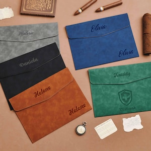 Peut inclure: Plusieurs porte-documents personnalisés de couleurs variées : gris, noir, marron, bleu et vert. Chaque porte-document affiche un nom ou texte, l'un d'eux présente un écusson. Accessoires : cigares, montre de poche et document roulé.