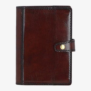 May include: A brown leather notebook with a gold button closure. The notebook has a flap that folds over the front cover.