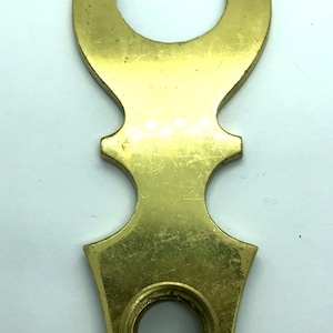 May include: A brass door plate with two keyholes and an ornate design.