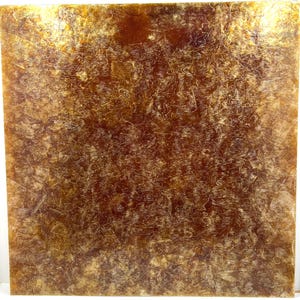 May include: A square, textured surface with a warm, amber color. The surface has a mottled appearance with lighter, fibrous details throughout. The overall effect is reminiscent of aged parchment or a natural material.