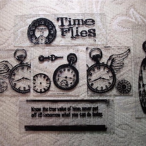May include: A set of clear rubber stamps with black ink featuring a clock with wings, a quote about time, and other clock designs. The quote reads "Know the true value of time, never put off till tomorrow what you can do today."
