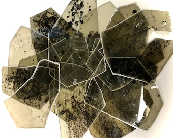 May include: A collection of translucent, irregularly shaped, dark brown mica flakes with black flecks. The mica is arranged in a cluster, with some pieces overlapping.
