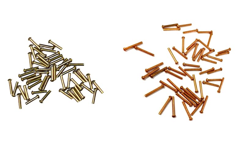 May include: A pile of gold-colored metal rivets and a pile of copper-colored metal rivets.