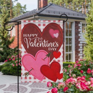 May include: A Valentine's Day garden flag with a red and white checkered background. The flag features a large burgundy heart with the words "Happy Valentine's Day" and several pink and red hearts. One pink heart is pierced by an arrow.