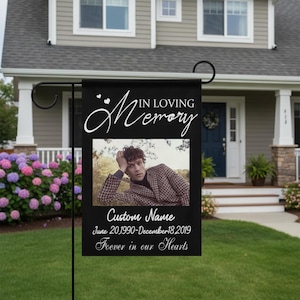Könnte beinhalten: Schwarze Gartenflagge mit dem Text "IN LOVING Memory" und einem Foto einer Person. Unter dem Foto steht der Text "Custom Name" und Daten. Die Flagge wird vor einem Haus gezeigt.
