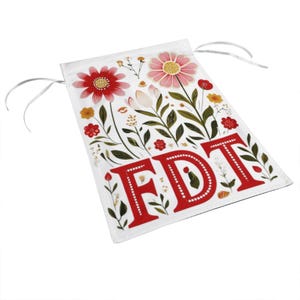 May include: White drawstring bag with a floral design and the letters "FDT" in red. The bag features red and pink flowers, green leaves, and small yellow flowers. The drawstring is silver.