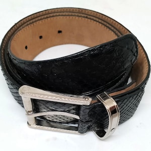 May include: A black leather belt with a silver buckle. The belt is made of snakeskin and has a smooth, polished finish.
