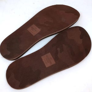 May include: A pair of brown rubber flip-flop soles with the text "VALENTINO GARAVANI" printed on one sole and "32 VALENTINO" printed on the other sole.