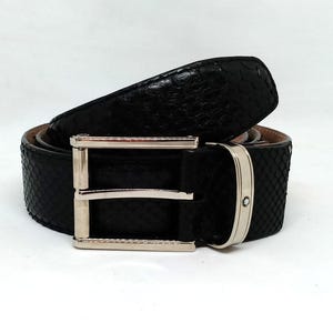 Könnte beinhalten: Ein schwarzer Ledergürtel mit einer silbernen Schnalle. Der Gürtel ist aus strukturiertem Leder, das Schlangenleder ähnelt.