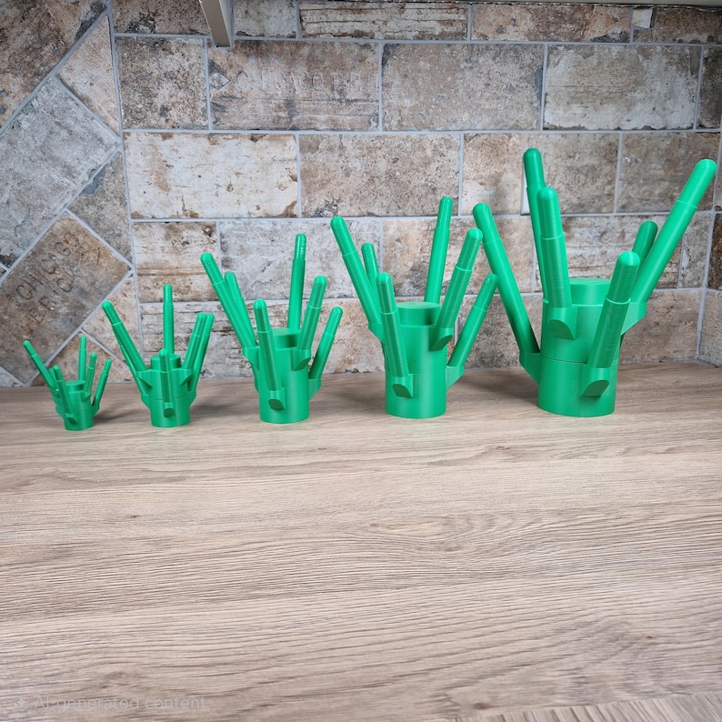May include: A set of five green 3D-printed cactus-shaped holders. Each holder has a cylindrical base with multiple upward-pointing, rod-like structures. The holders vary in size, with the smallest on the left and the largest on the right.