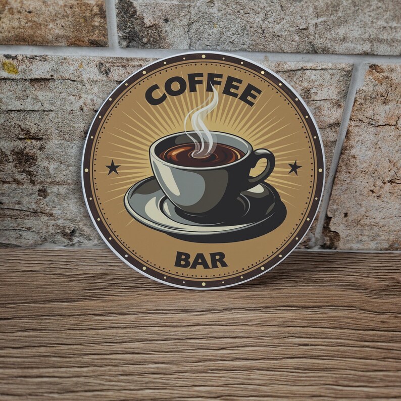 May include: Round coffee bar sign featuring a steaming cup of coffee on a saucer. The sign has a brown background with a sunburst design and the words "COFFEE BAR" in black. Two small stars are on either side of the cup.