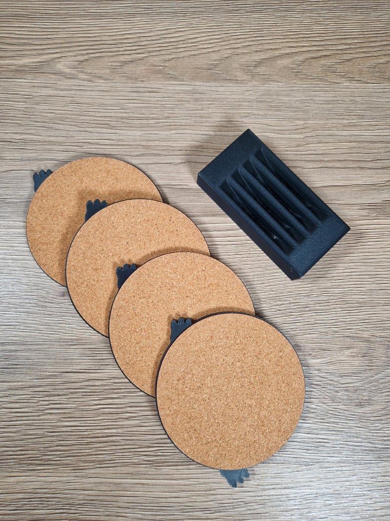 May include: Four round cork coasters with dark blue accents and a matching holder. The coasters are arranged in a diagonal line, showcasing their natural cork texture. The holder is rectangular with slots for coaster storage.