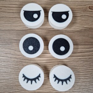 Puede incluir: Seis recortes de espuma blancos y circulares con dise&ntilde;os de ojos negros. Dos recortes tienen cejas negras y formas de ojos, dos tienen c&iacute;rculos negros con puntos blancos y dos tienen pesta&ntilde;as negras.