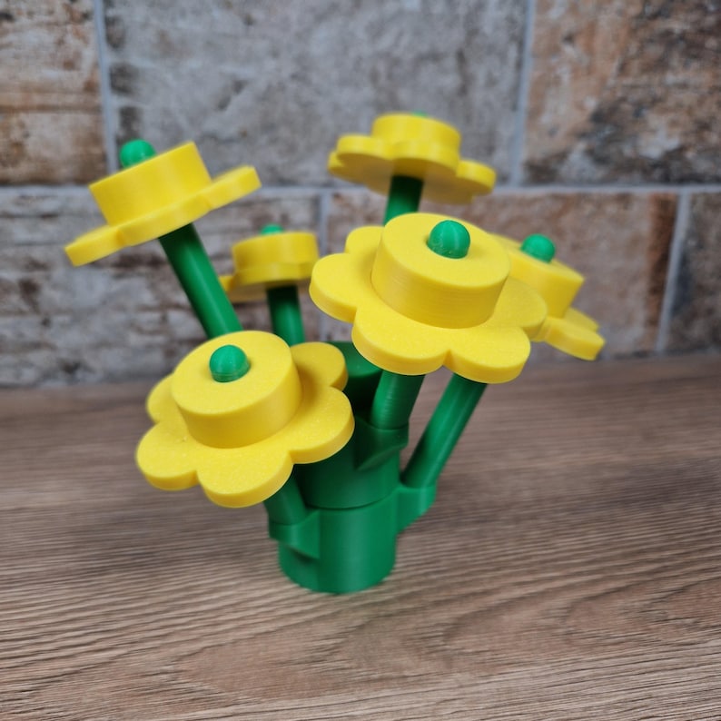 May include: A bouquet of yellow and green plastic flowers. The flowers have yellow petals and a green center. The stems are green, and the base is a green vase-like structure. The flowers are arranged in a cluster, creating a cheerful display.