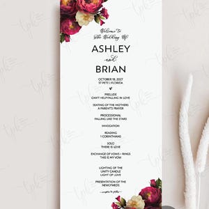 May include: A vertical wedding program card featuring a white background with deep magenta and cream floral arrangements at the top and bottom corners. The text reads Welcome To The Wedding Of ASHLEY and BRIAN, October 18, 2027, and lists ceremony events.