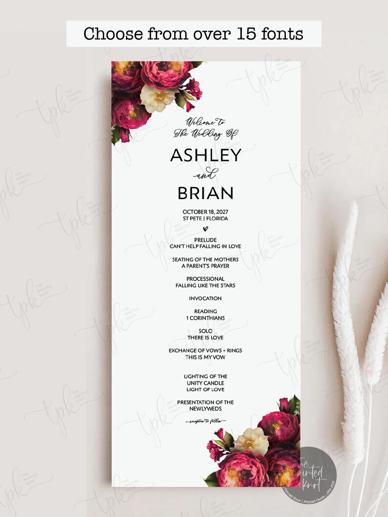 May include: A vertical wedding program card featuring a white background with deep magenta and cream floral arrangements at the top and bottom corners. The text reads Welcome To The Wedding Of ASHLEY and BRIAN, October 18, 2027, and lists ceremony events.