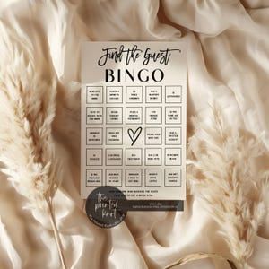 May include: A white Bingo card with black text reading "Find the Guest BINGO". The card features a grid of prompts and a heart graphic. The Printed Knot logo is at the bottom. Ideal for a bridal shower or party.